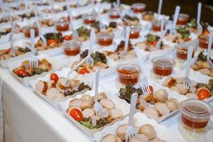 Würstchen im Pappteller mit Tomate, Gemüse und Gabel in der Linie auf dem Tisch sind servierfertig. foto