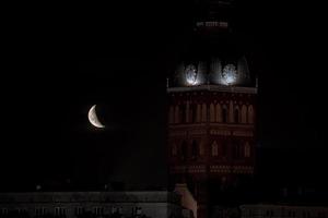 schöner Viertelmond über der Altstadt von Riga hinter Kuppeln Domuhr. foto