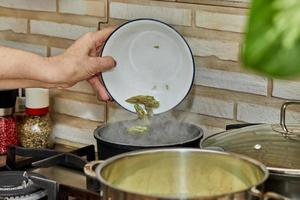 Koch wirft Spargelköpfe in einen Topf auf einem Gasherd foto