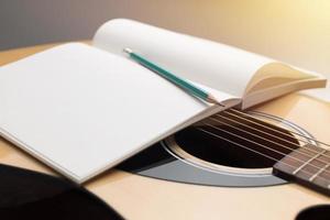 Komponieren Sie Musik, Bleistift und Notizbuch auf der Akustikgitarre foto