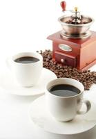 Tassen Kaffee mit Untertasse und Mühle auf Weiß