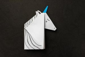 Weißes Einhorn in Origami-Technik auf schwarzem Hintergrund. mit Platz für Ihren Text. foto