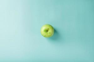 Ein grüner Apfel auf grünem Hintergrund mit einer minimalistischen Komposition. foto