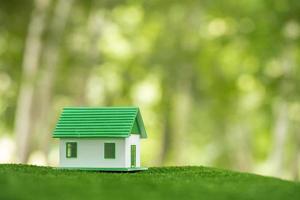 umweltfreundliches immobilienhaus. kleines Modellbaugrundstück auf Gras in grüner Naturökologie. nachhaltige energieeinsparung wohndesign und verkauf - miete geschäftskonzept foto