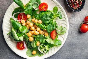 Gemüsesalat Kichererbsen, Hülsenfrüchte, Kopfsalat, Mache, Tomate frische gesunde Mahlzeit Lebensmittel Snack Diät auf dem Tisch kopieren Raum Lebensmittel Hintergrund foto