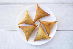 samosas auf weißer platte auf weißem holz. draufsicht. foto