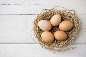 Schließen Sie herauf frische organische Eier auf Nest auf weißem hölzernem Hintergrund. foto