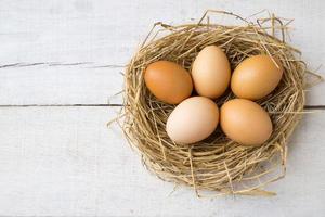 Draufsicht frische Bio-Eier auf Nest auf weißem Holzhintergrund. foto
