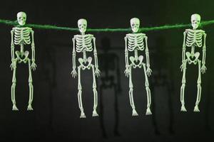 Vier Skelette, die am Hals an einem Seil aufgehängt sind, mit Silhouetten auf dunklem Hintergrund foto