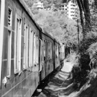 spielzeugeisenbahn, die sich am berghang bewegt, schöne aussicht, eine seite des berges, eine seite des tals, die auf der eisenbahn zum hügel fährt, inmitten grüner naturwälder. spielzeugeisenbahn von kalka nach shimla in indien-schwarz und weiß foto