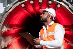 Der Chefingenieur der mechanischen Anlage führt eine Inspektion des Tunnels der Sterilisationsmaschine durch. um den Betriebszustand der Maschine zu überprüfen, um bereit zu sein foto