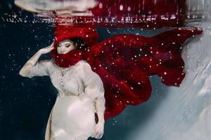 Frau mit rotem Hut und rotem Schal unter Wasser foto