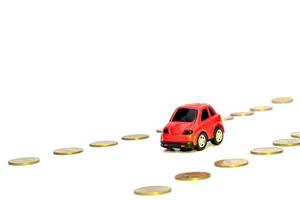 rotes Spielzeugauto und Haufen von Münzen a isoliert auf weißem Hintergrund foto