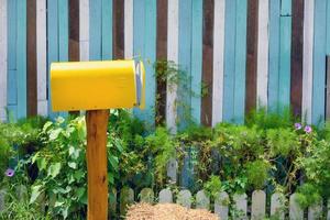 Gelber Vintage-Briefkasten mit Holzwand im Garten foto