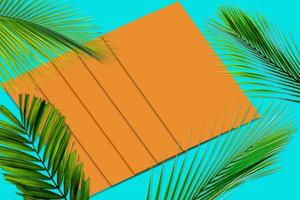 grünes palmblattmuster für naturkonzept, tropisches blatt auf orange und blaugrünem papierhintergrund foto
