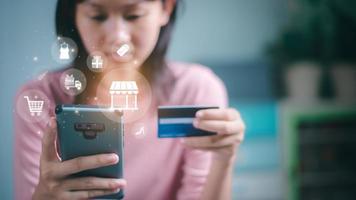 Eine Frau verwendet eine Kreditkarte für Finanztransaktionen auf ihrem Smartphone. Zahlungskonzept mit drahtloser Kommunikationstechnologie, Einkaufsservice im Online-Web und Angeboten für die Lieferung nach Hause.