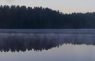 Morgennebel auf dem See. Reflexionsbäume auf dem Wasser. foto