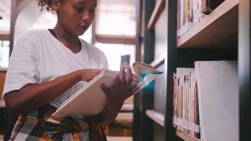 ein schulmädchen sucht im bücherregal der bibliothek nach büchern zur prüfungsvorbereitung. foto