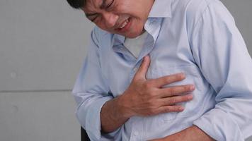 asiatischer mann hat brustschmerzen, die durch eine herzerkrankung verursacht werden.
