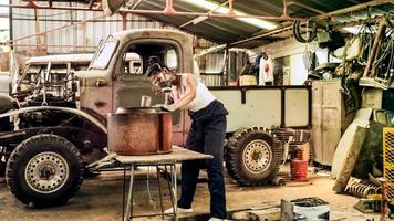 attraktive junge frau mechanischer arbeiter, der einen oldtimer in der alten garage repariert. foto