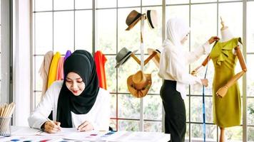schöne muslimische frau, die kleidersilhouette im büro skizziert. foto