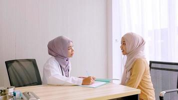 muslimische ärztin, die mit patientin im krankenzimmer spricht. foto