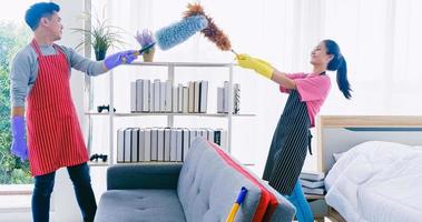 Mann und Frau reinigen gemeinsam ihr Zimmer. glückliches asiatisches paar, das zeit zusammen zu hause verbringt. foto