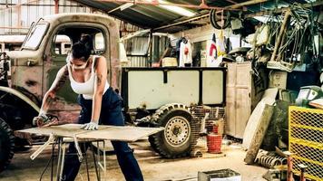 attraktive junge frau mechanischer arbeiter, der einen oldtimer in der alten garage repariert. foto