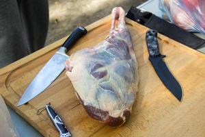 frisches und rohes Fleisch. Lammkeule mit Messern auf Schneidebrett foto