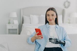 glückliches Mädchen hält Glas Wasser mit Cyber-Handprothese. futuristische Medizintechnik. foto