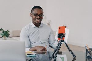 Afro-Freiberufler hat Online-Brainstorming auf dem Smartphone. glücklicher Mann zeigt Papierkram mit Daten. foto