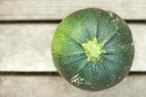 grüne runde zucchini lokalisiert auf hölzernem hintergrund. foto