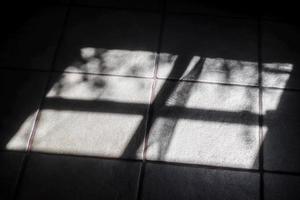 abstraktes konzept der weichen schatten des sonnenlichts durch ein fenster auf einem fliesenhintergrund foto