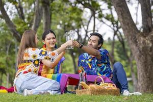 gruppe von transgender- und homosexuellen menschen jubelt und feiert den lgbtq-stolzmonat in buntem kleid und regenbogenfahne beim picknick im parkkonzept foto