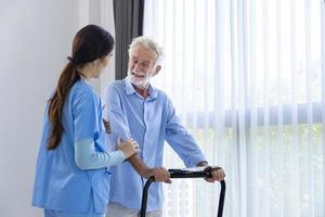 Die Hospizkrankenschwester unterstützt den kaukasischen Mann beim Gehen mit dem Laufband im Rentenzentrum für die Rehabilitation der häuslichen Pflege und den Genesungsprozess nach der Behandlung foto