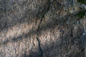 roher Granitfelsen-Texturhintergrund. Fragment einer Natursteinmauer. foto