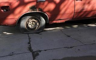 Kaputtes Auto mit Rostschäden und einem platten Reifen foto