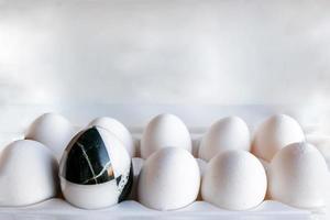 Eier in verschiedenen Farben in Kartons. Marmorsteinei auf einem Hintergrund aus weißen Hühnereiern foto