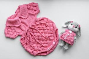 schöne Baby-Strickkleidung und ein Spielzeug für ein neugeborenes Baby foto