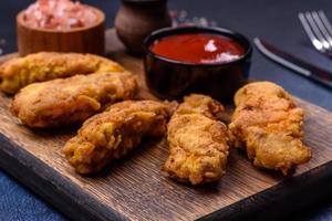 frittierte knusprige Chicken Nuggets mit Ketchup auf schwarzem Teller auf dunklem Hintergrund foto