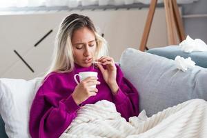 tausendjährige kranke frau, die schmerzmittel einnimmt, um bauchschmerzen zu lindern, sitzt morgens auf dem bett foto