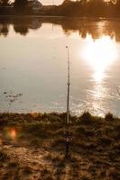 Angeln bei Sonnenuntergang. Fischer mit Spinnrute. fischer mit rute, spinnrolle am flussufer. Angeln auf Hecht, Barsch, Karpfen. wilde Natur. Artikel über Angeltag. selektiver Fokus auf Angelrute foto