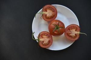 reife schöne tomatenfrucht auf einer weißen plattendraufsicht. köstliches tomatenstillleben. foto