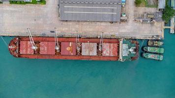 Luftbild von der Drohne eines Handelsschiffs mit Kränen beim Entladen von Containern auf ein großes Handelsschiff im Kai. transport- und reisehintergrund, schönes meer im sommer. foto