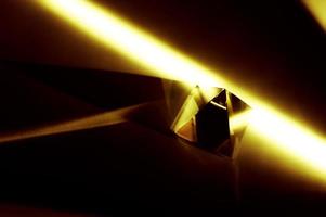 abstraktes Bild einer Kristallpyramide mit goldgelben hellen Lichtstrahlen. foto