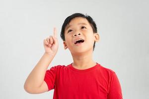 wow schau, werbe hier, porträt eines erstaunten süßen kleinen jungen mit lockigem haar, der auf einen leeren platz im hintergrund zeigt foto