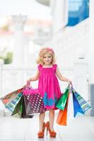 kleines Mädchen mit Einkaufstüten geht in den Laden