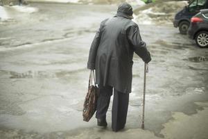 Frau mit Porenstab geht beim Gehen die Straße hinunter. Rentner in Russland. foto