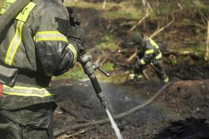 Feuerwehrmann gießt Wasser aus Schlauch. Brandbekämpfung im Detail. Wasser aus Hydranten. foto