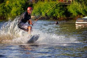 Geschwindigkeitsrennen eines Wakeboarders auf einem Wasserbrett an einem Sommertag. hochfliegende Wasserspritzer von einem Wasserbrett. 19.06.1922. Kiew. Ukraine. foto